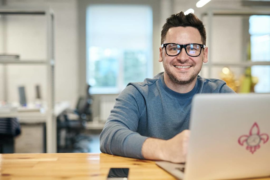 Man with glasses smiling about SEO Services in Florida while at his laptop